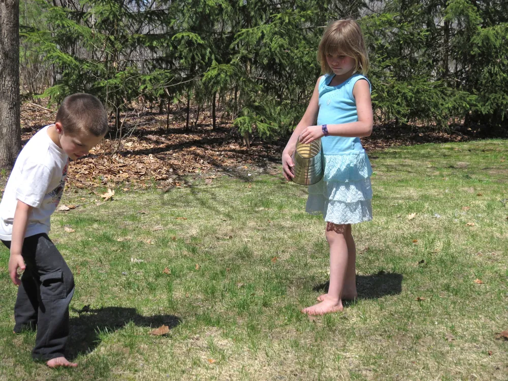 Two children scattering birdseed in a snowy backyard.